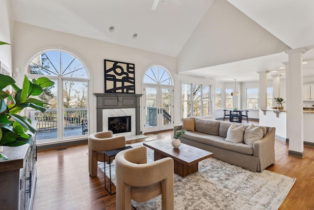 living room featuring a fireplace, decorative columns, hardwood / wood-style floors, and a wealth of natural light