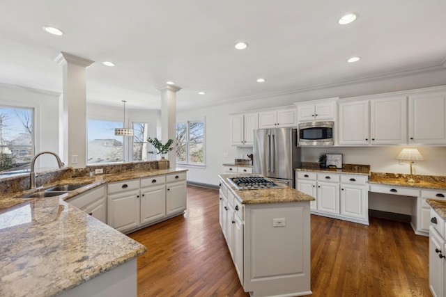 kitchen featuring sink, white cabinetry, decorative light fixtures, appliances with stainless steel finishes, and a kitchen island