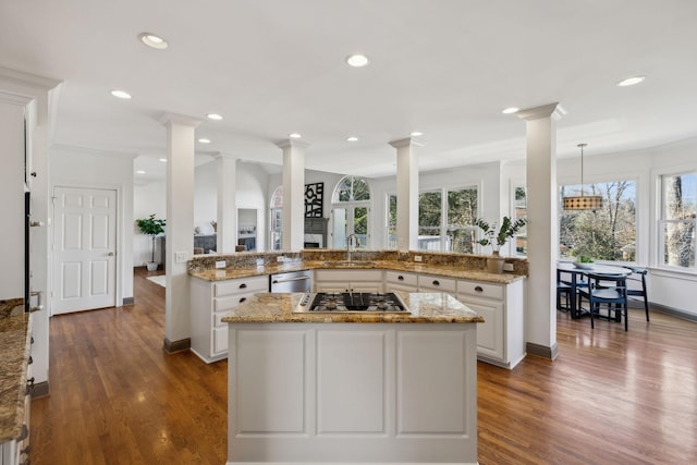 kitchen with appliances with stainless steel finishes, decorative columns, white cabinetry, sink, and kitchen peninsula