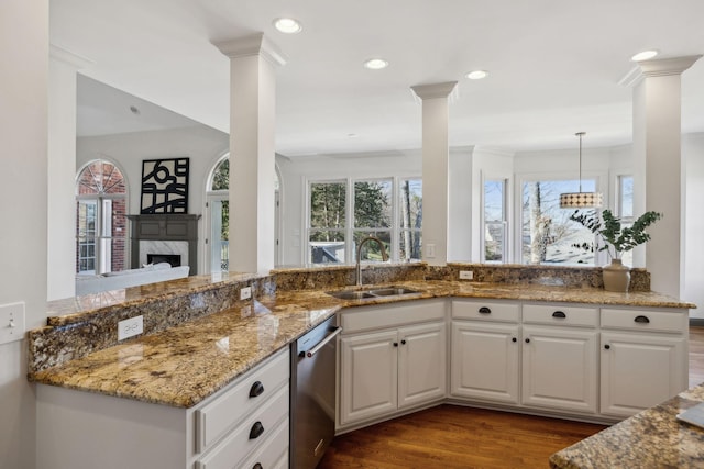 kitchen featuring white cabinetry, sink, stainless steel dishwasher, and decorative light fixtures