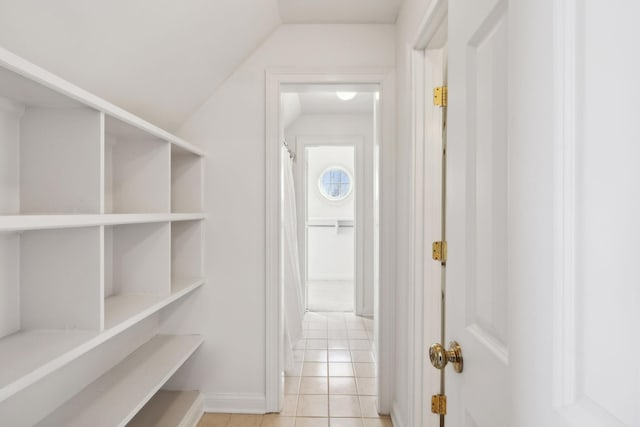 hallway with lofted ceiling and light tile patterned floors