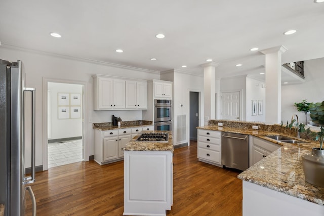 kitchen featuring sink, appliances with stainless steel finishes, kitchen peninsula, light stone countertops, and white cabinets