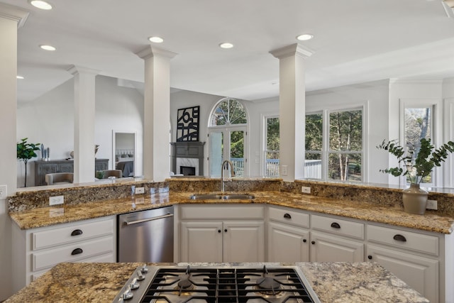 kitchen featuring decorative columns, white cabinetry, sink, and dark stone countertops