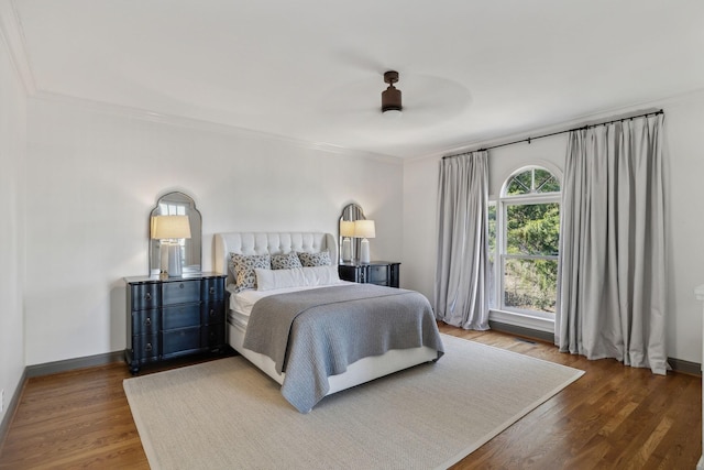 bedroom featuring crown molding, dark wood-type flooring, and ceiling fan