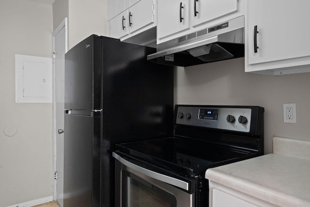 kitchen featuring white cabinetry, black fridge, and electric stove