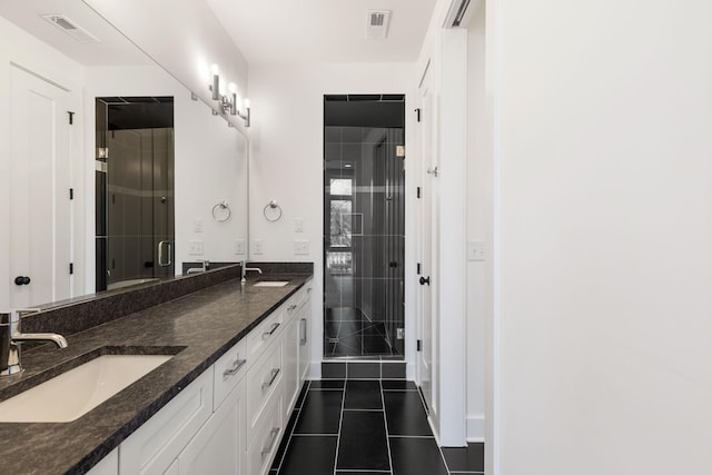 bathroom with a shower with door, vanity, and tile patterned floors