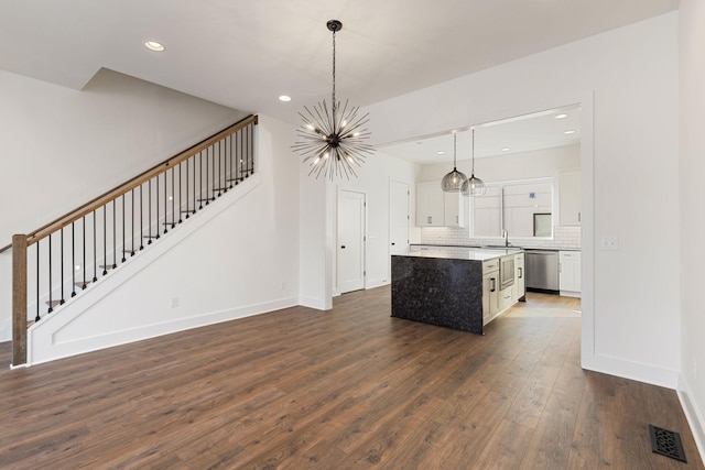 kitchen with dishwasher, backsplash, white cabinets, a kitchen island, and decorative light fixtures