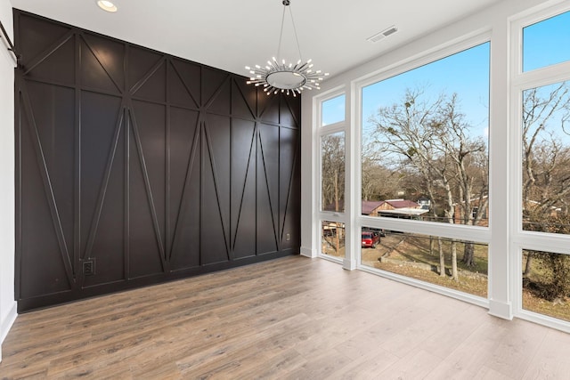 spare room with a chandelier and light wood-type flooring