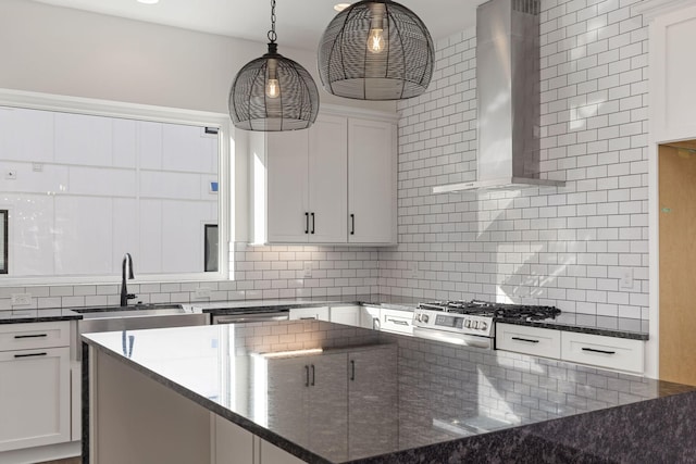 kitchen featuring wall chimney exhaust hood, white cabinetry, tasteful backsplash, dark stone countertops, and stainless steel range