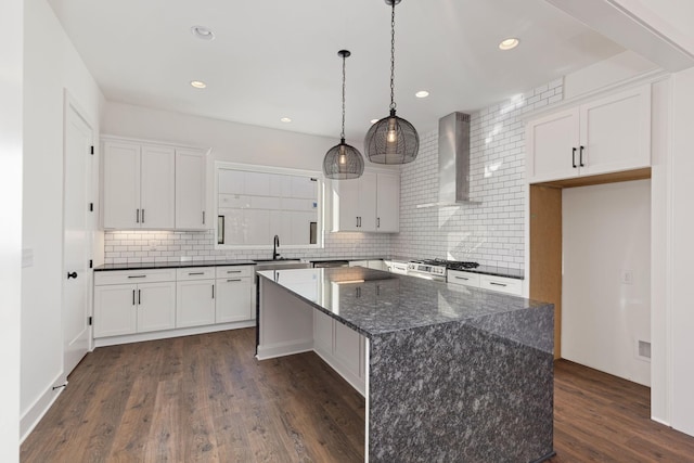 kitchen featuring white cabinetry, wall chimney range hood, pendant lighting, and a center island