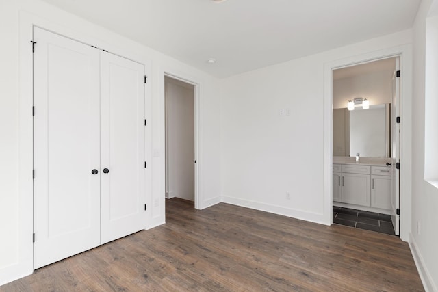 unfurnished bedroom featuring sink, dark hardwood / wood-style floors, connected bathroom, and a closet