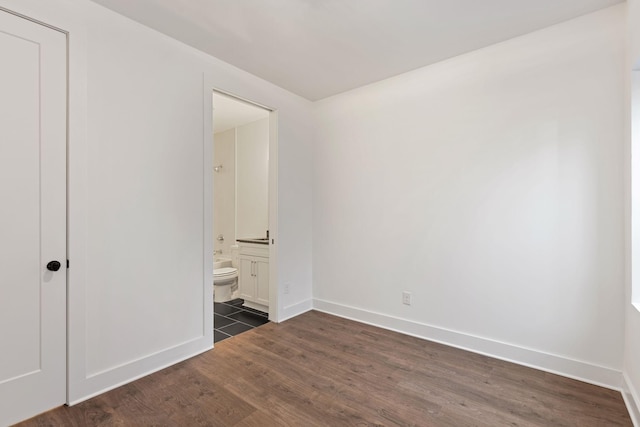 unfurnished bedroom with dark hardwood / wood-style flooring and ensuite bath