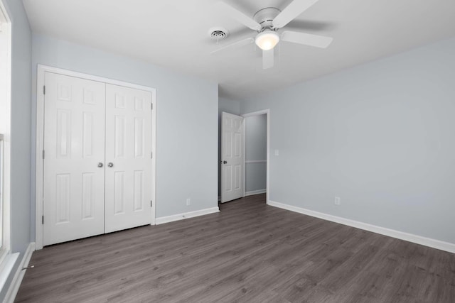 unfurnished bedroom featuring baseboards, visible vents, dark wood-style flooring, ceiling fan, and a closet