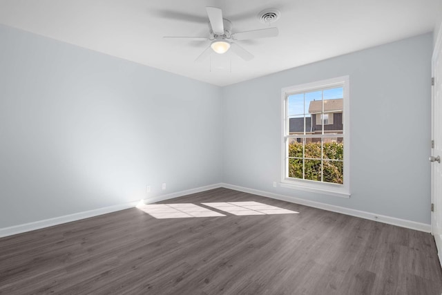 spare room with visible vents, baseboards, dark wood-style floors, and a ceiling fan