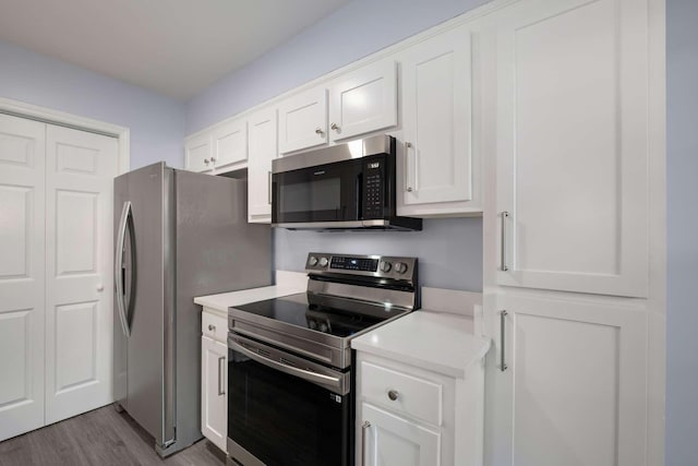 kitchen with light countertops, white cabinets, dark wood-type flooring, and appliances with stainless steel finishes