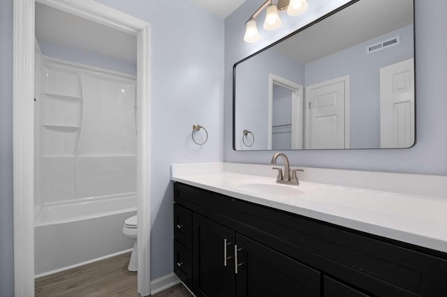 bathroom featuring visible vents, toilet, shower / bathtub combination, wood finished floors, and vanity