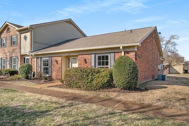 traditional-style home with brick siding, roof with shingles, and a front lawn