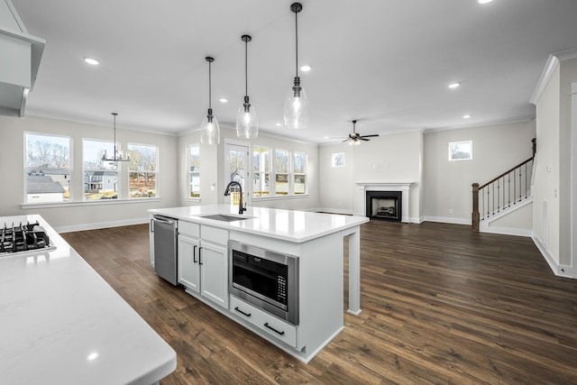 kitchen featuring dark wood-type flooring, sink, hanging light fixtures, a center island with sink, and stainless steel appliances