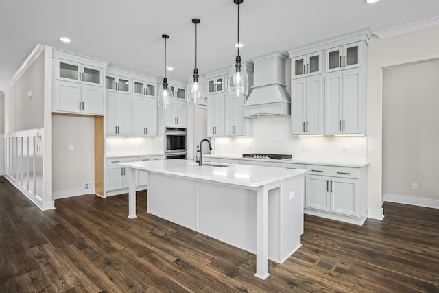 kitchen with white cabinetry, premium range hood, sink, and a center island with sink