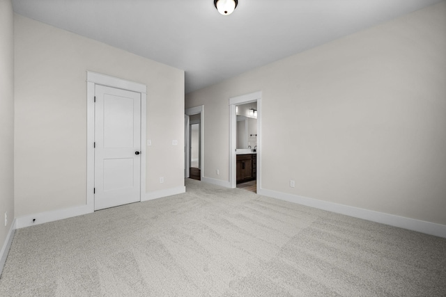 unfurnished bedroom featuring connected bathroom, light carpet, and a closet