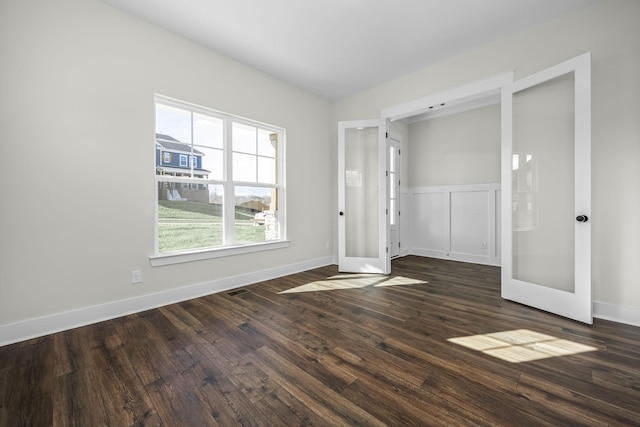 empty room with dark hardwood / wood-style flooring and french doors