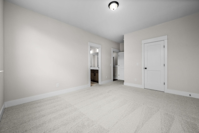 unfurnished bedroom with ensuite bathroom, light carpet, and a closet