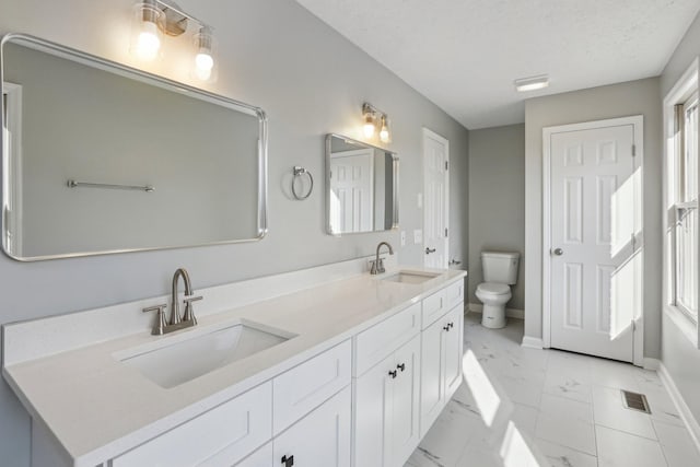 bathroom featuring vanity, a textured ceiling, and toilet