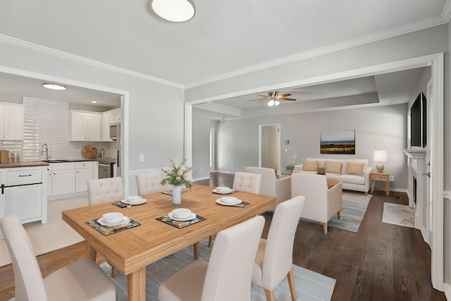 dining space with sink, wood-type flooring, ornamental molding, and ceiling fan