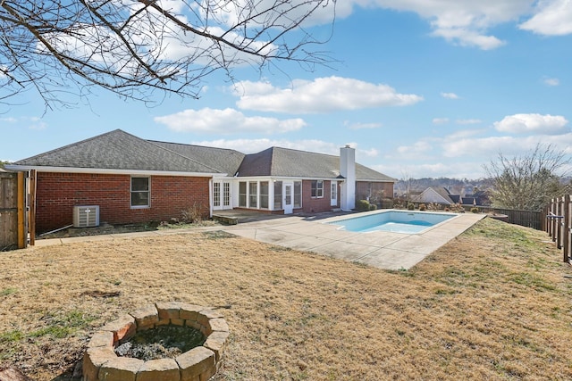 back of house with a fenced in pool, a fire pit, a lawn, central AC, and a patio area