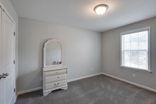 unfurnished bedroom with dark colored carpet and baseboards