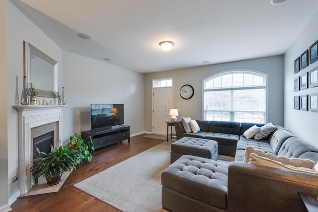 living room with a glass covered fireplace, dark wood-style flooring, and baseboards