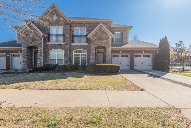 view of front of home featuring a balcony, a garage, brick siding, concrete driveway, and a front lawn