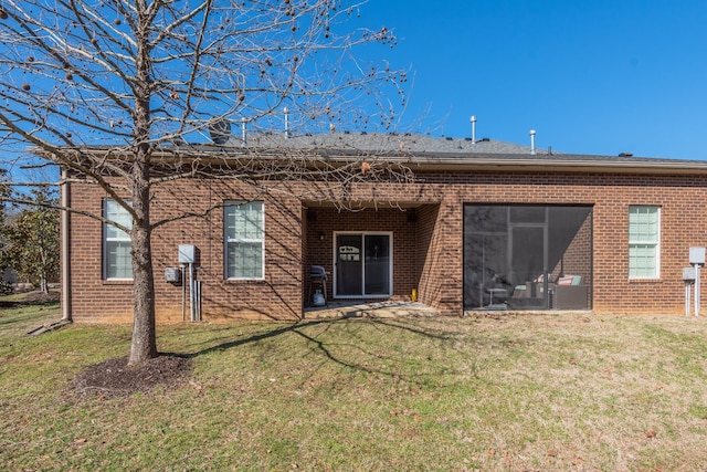 rear view of house with brick siding and a yard