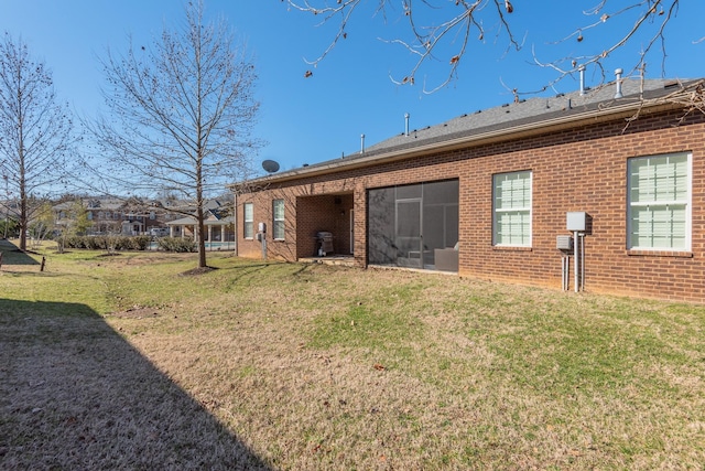 back of house with a yard and brick siding