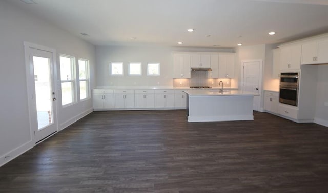 kitchen with white cabinetry, sink, stainless steel double oven, and a center island with sink