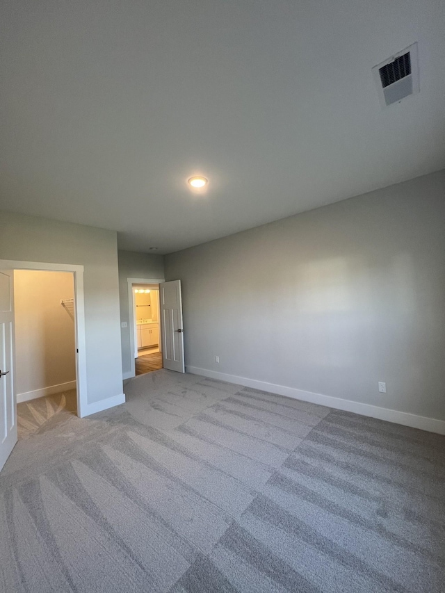 unfurnished bedroom featuring a walk in closet and light carpet