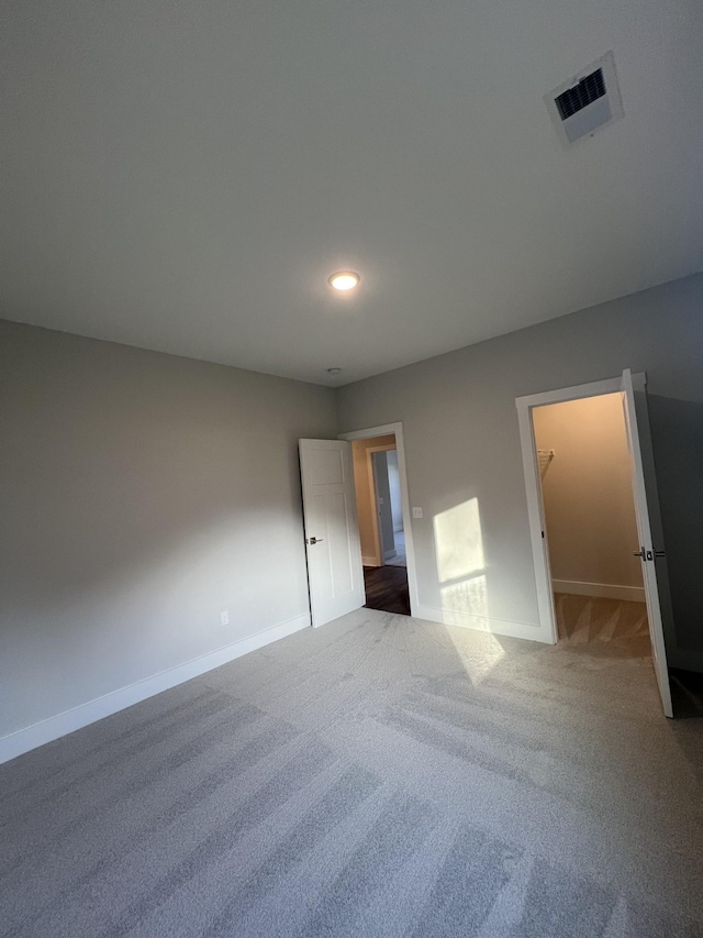 unfurnished bedroom with a walk in closet and carpet flooring