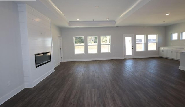 unfurnished living room with dark wood-type flooring, a fireplace, and a raised ceiling