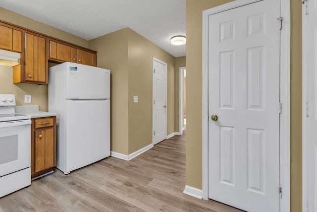 kitchen with white appliances, a textured ceiling, and light wood-type flooring