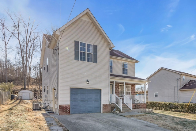 view of property featuring a porch, a garage, a storage shed, and central air condition unit