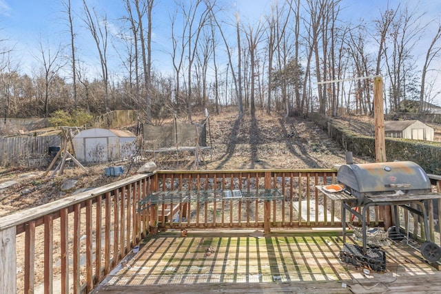 wooden deck with a grill, a trampoline, and a storage unit