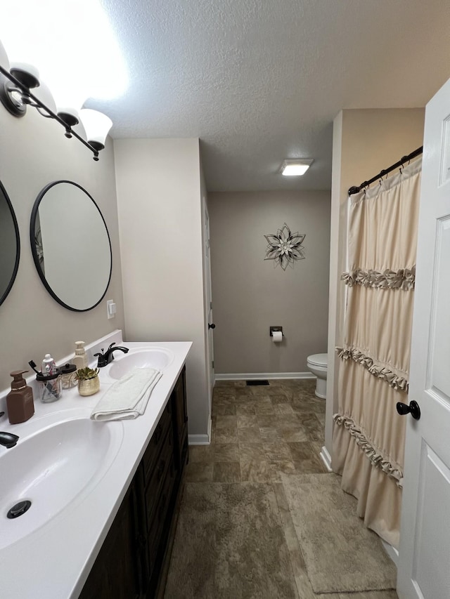 bathroom featuring vanity, toilet, and a textured ceiling