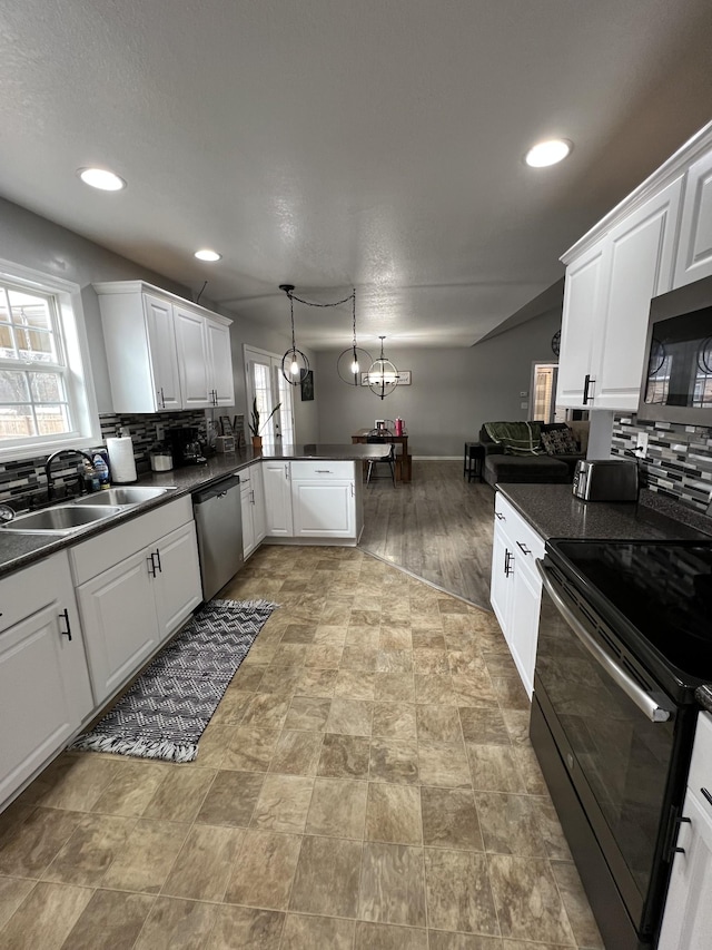 kitchen with pendant lighting, sink, white cabinetry, stainless steel appliances, and kitchen peninsula