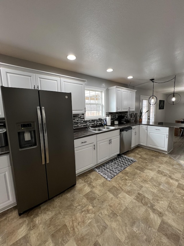 kitchen with pendant lighting, sink, white cabinets, kitchen peninsula, and stainless steel appliances