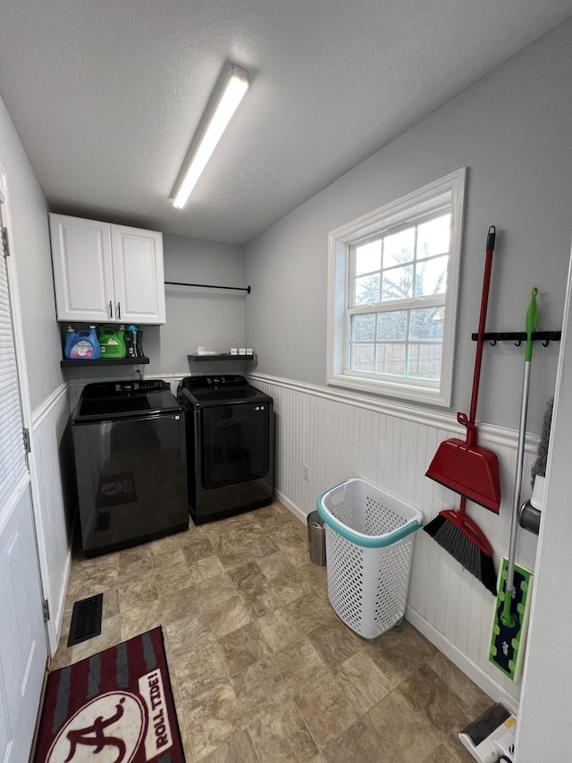 washroom with cabinets, a textured ceiling, and washer and clothes dryer