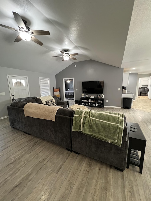 living room featuring wood-type flooring, vaulted ceiling, ceiling fan, and a textured ceiling