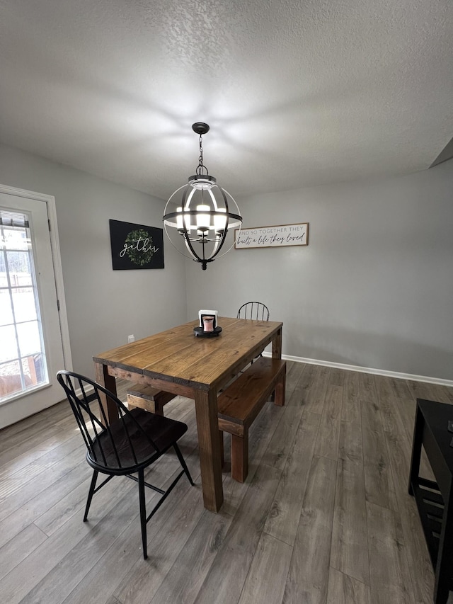 dining room with wood-type flooring, a textured ceiling, and an inviting chandelier