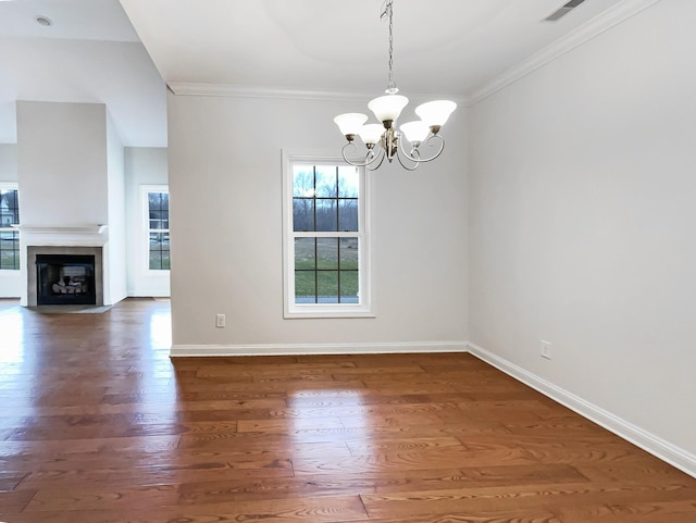 unfurnished dining area featuring dark hardwood / wood-style flooring, ornamental molding, and an inviting chandelier