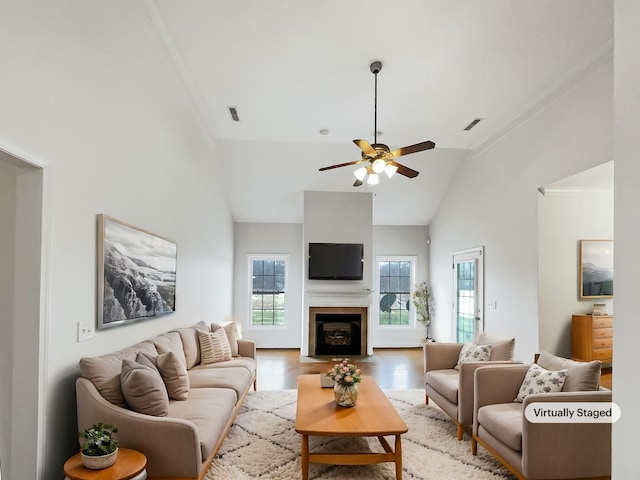 living room featuring ceiling fan, lofted ceiling, ornamental molding, and light wood-type flooring