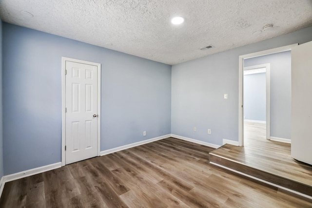 unfurnished room featuring hardwood / wood-style flooring and a textured ceiling